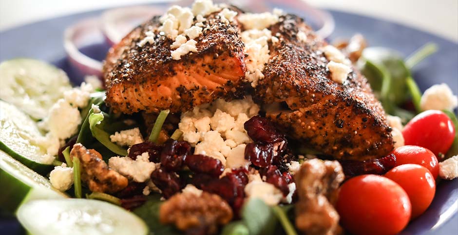 Salad with grilled salmon, feta cheese, cranberries, cucumber, lettuce and grape tomatoes