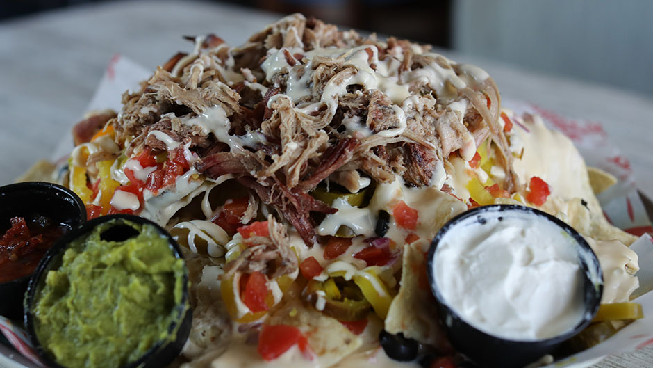 Corn chips loaded with tomatoes, onions, jalapeños, banana peppers, black olives, then smothered with our SandBar Queso. Topped with pulled pork